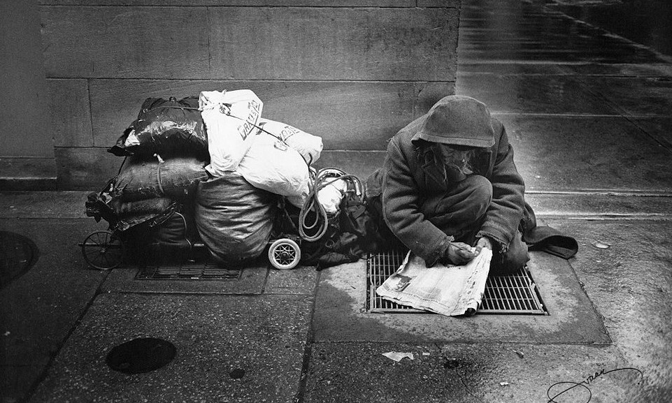 A homeless man working on a crossword puzzle.